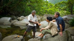 A couple receiving a tour in the jungle by a river